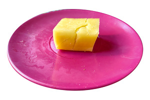 Piece of low-fat cheese placed on a red plastic plate isolated p, a Food & Drink Photo by DanFLCreativo