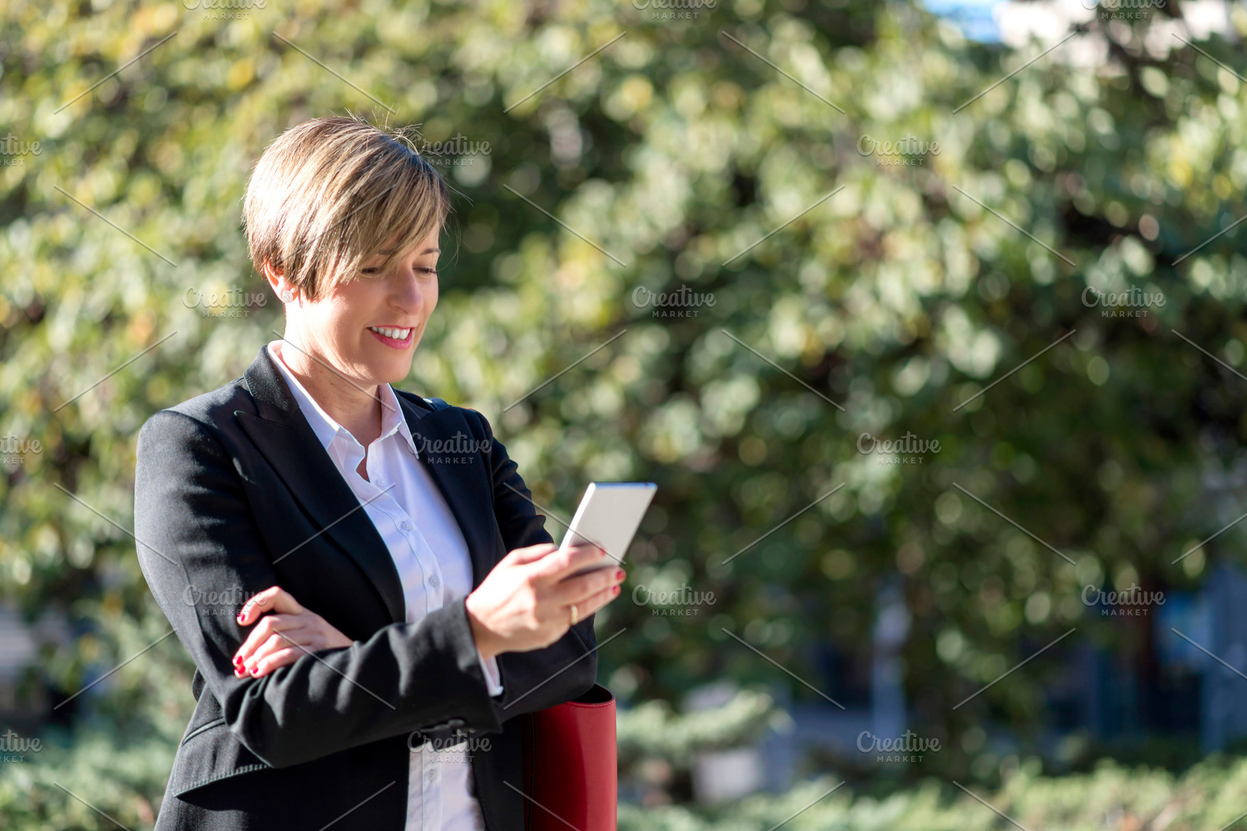 Businesswoman using smartphone outdoors in park, a Photo by RF Images