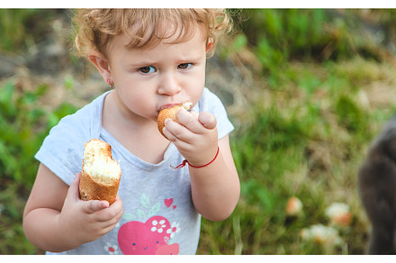 A child eats bread in the park, a Person Photo by yanadjana