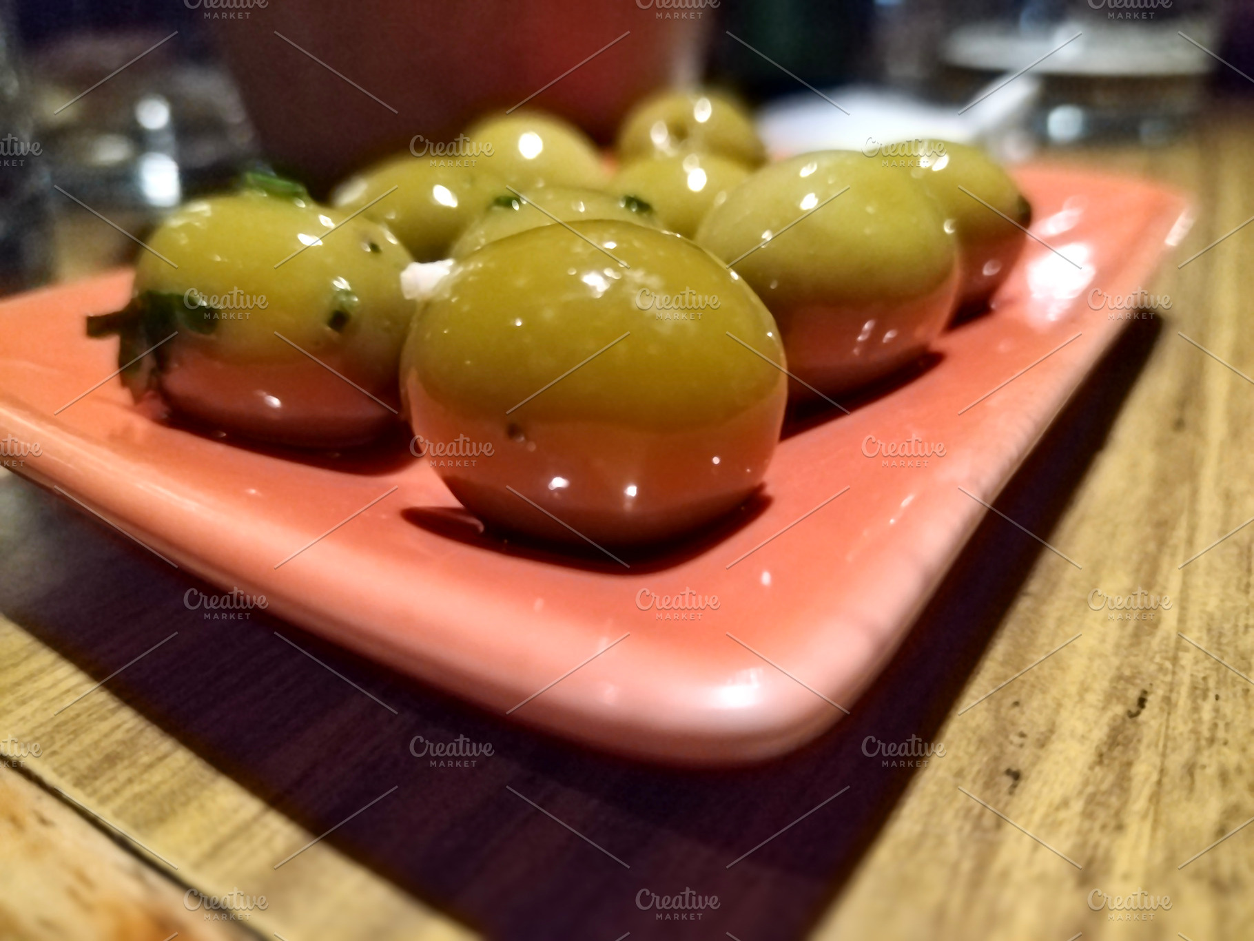Close-up of green olives on pink plate, a Food & Drink Photo by DanFLCreativo