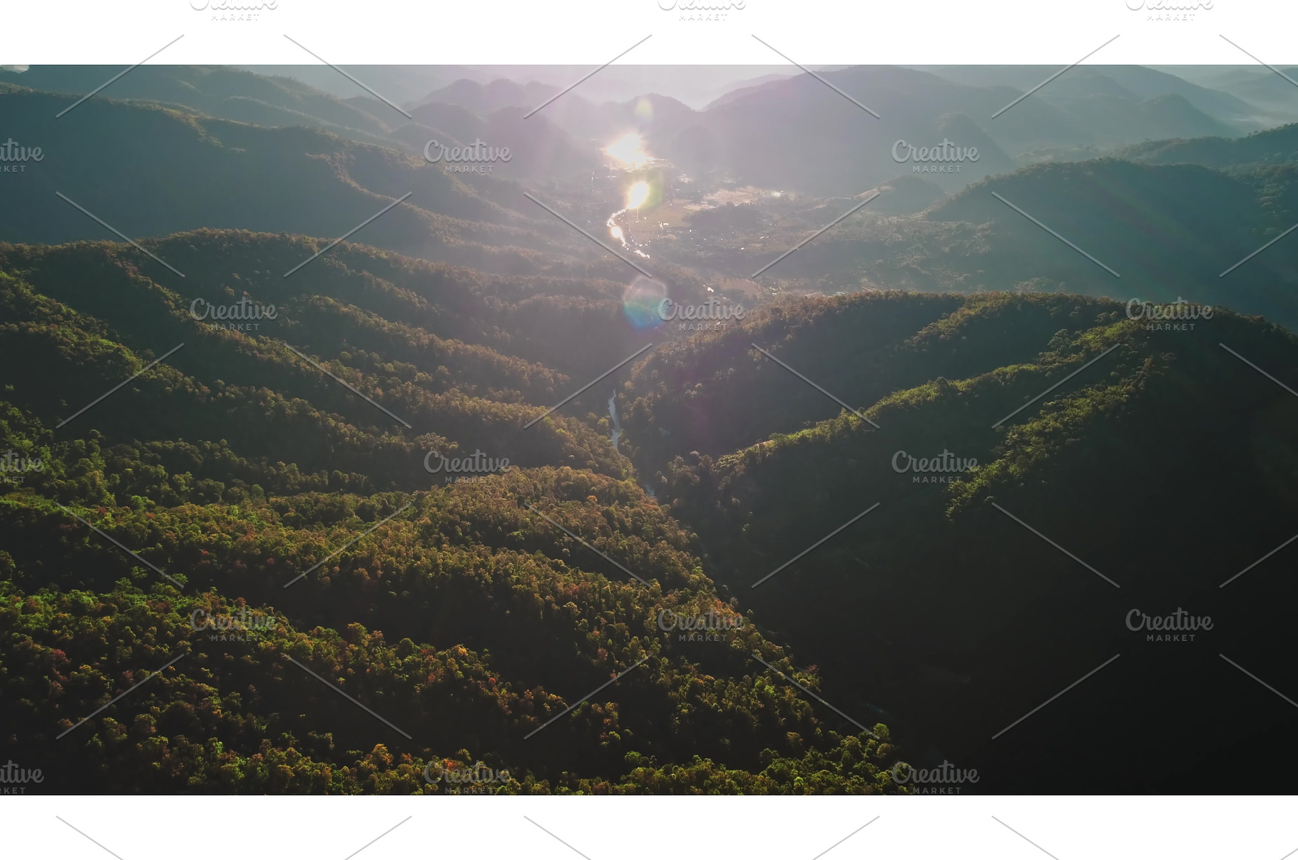 Sun shining over forested mountains, a Nature Photo by Goinyk