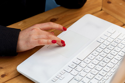 Female hands with red manicure on the background of a white laptop, a Technology Photo by Photostock