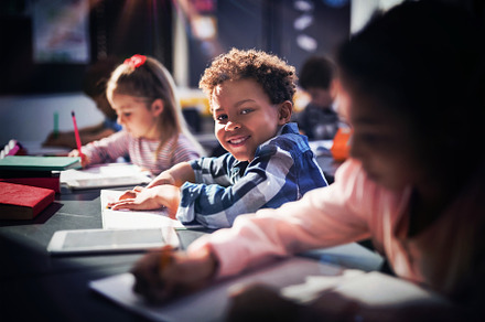 Smiling schoolboy doing his homework, a Photo by wavebreak