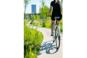 Female cyclist on sunny path in lush, a Sports & Recreation Photo by Lermont51
