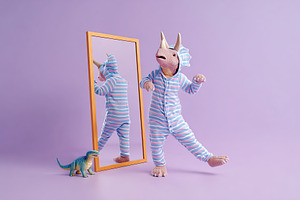 Dinosaur character in pajamas dancing beside a mirror with a toy dinosaur on a, an Animal Photo by AlyaAnd