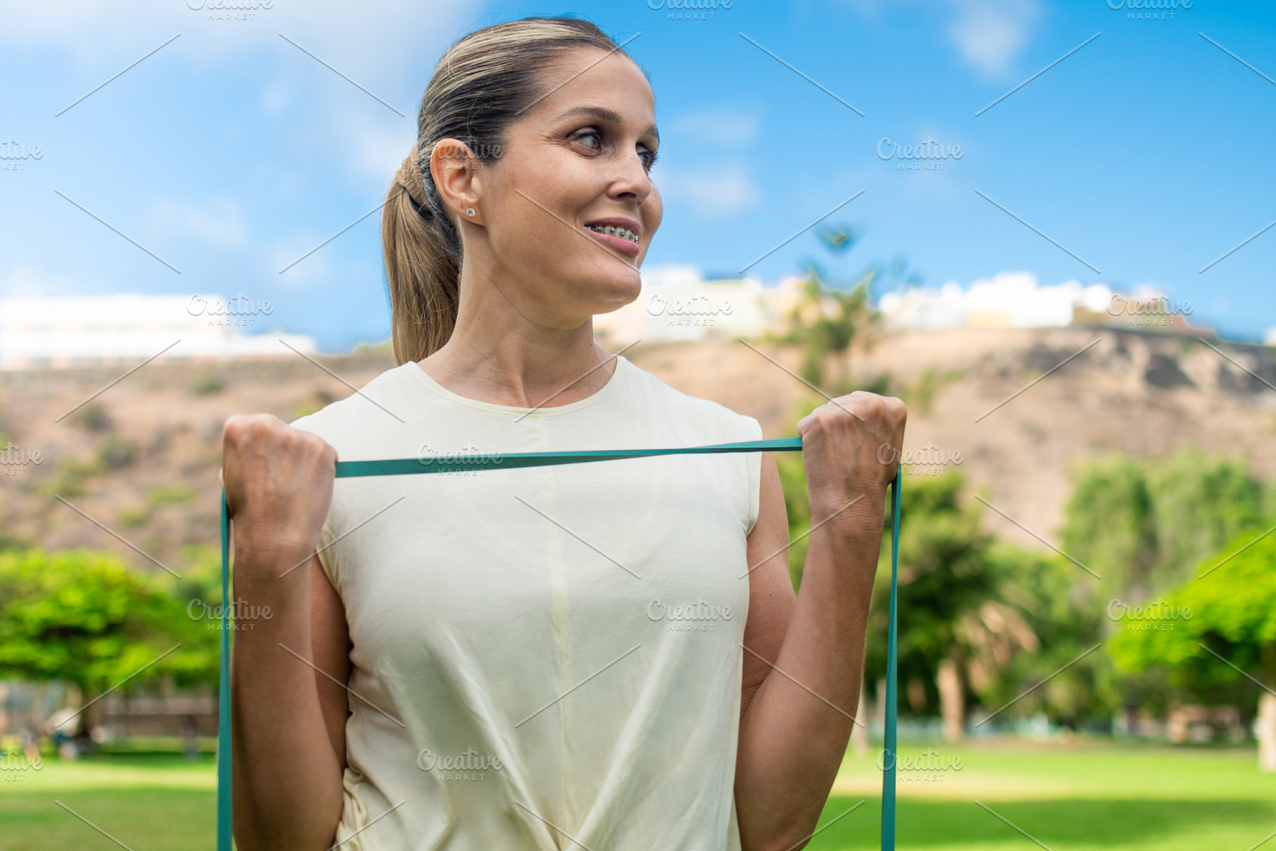 Smiling woman exercising with resistance band in park, a Sports & Recreation Photo by etorres69