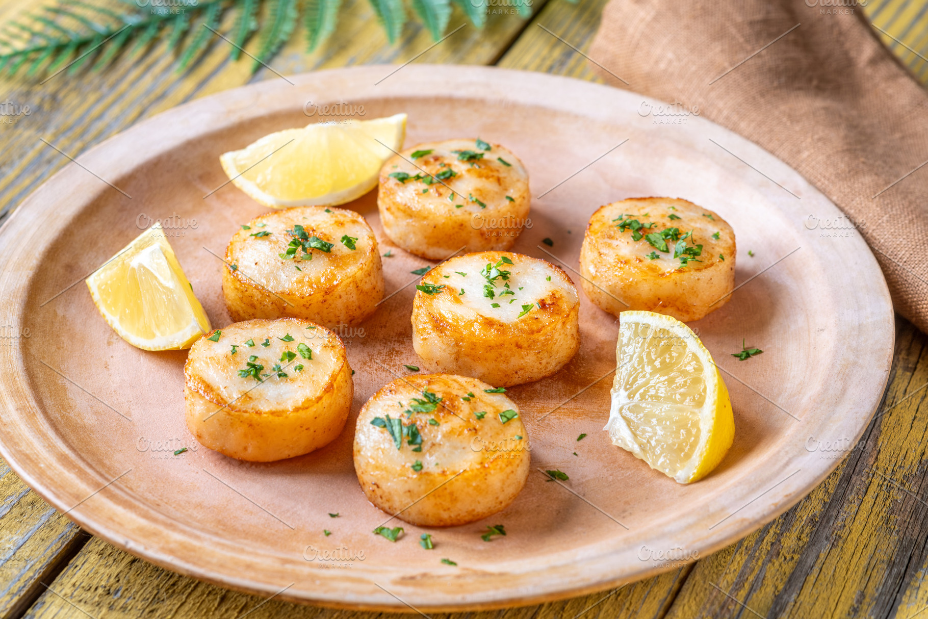 Fried scallops with butter, lemon, parsley on rustic yellow wood, a Food & Drink Photo by Alexander Prokopenko