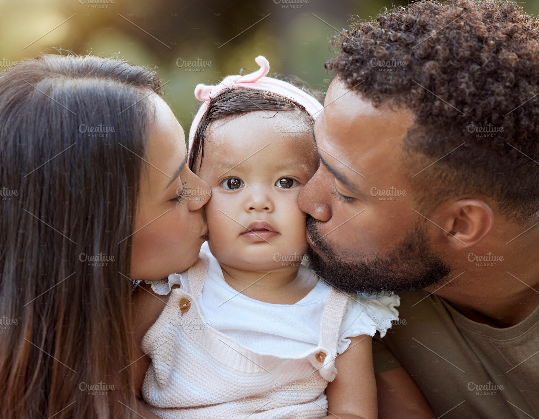 Mother, father and baby face kiss while bonding in a garden outdoors with love, care and affection. Loving, caring parents kissing little daughter while bond in nature for calm relaxation, a Photo by Peopleimages.com