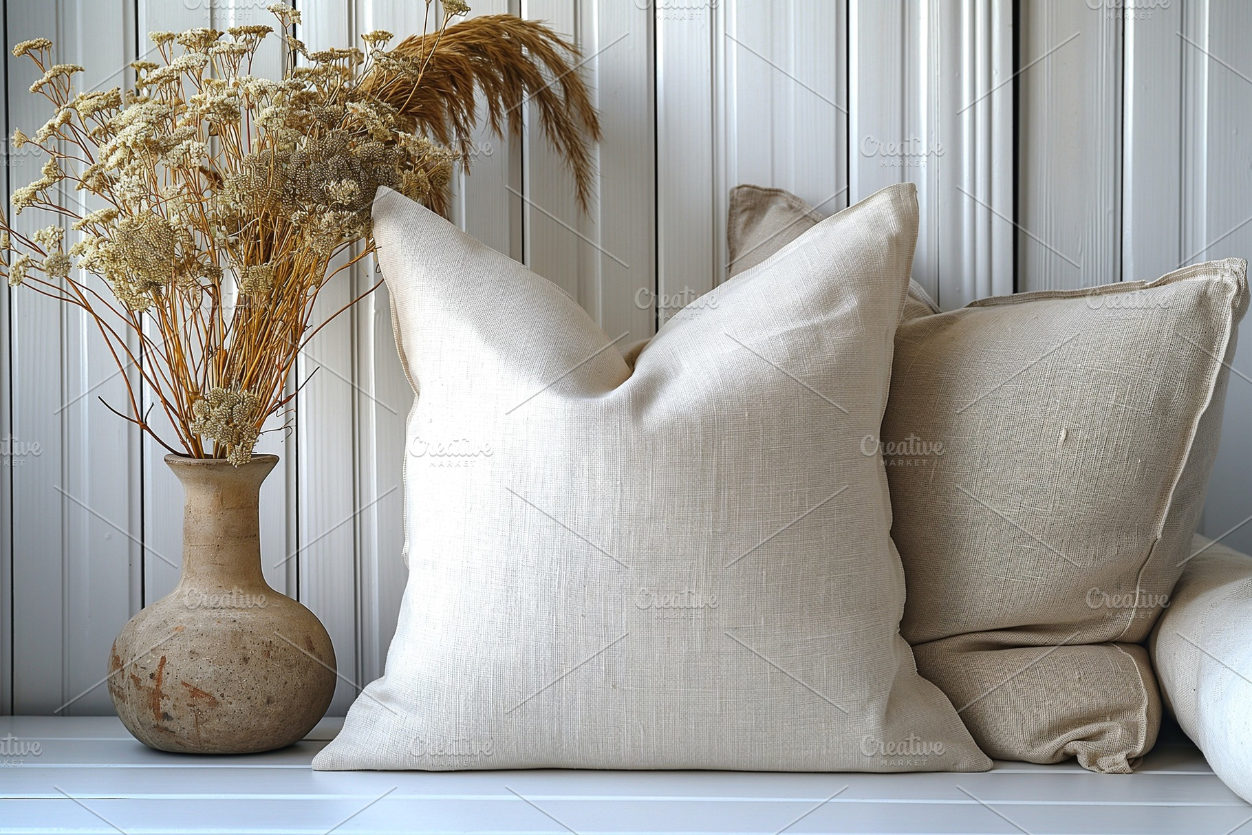 A cozy arrangement of light-colored pillows and dried flowers in a rustic vase,, a Business Photo by ImageMir