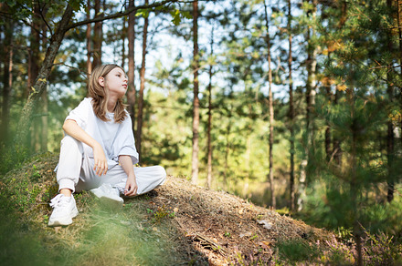 Young girl enjoying a sunny day in a forest clearing while sitti, a Person Photo by Olena Rudo