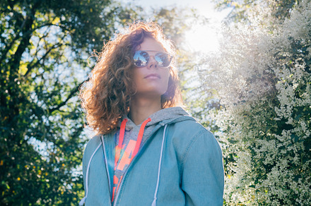 Young woman standing outdoors in green blooming park, a Person Photo by progressman