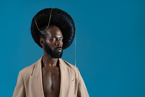 Serious black gay model wearing huge wig with chain on blue background, a Person Photo by andreonegin market