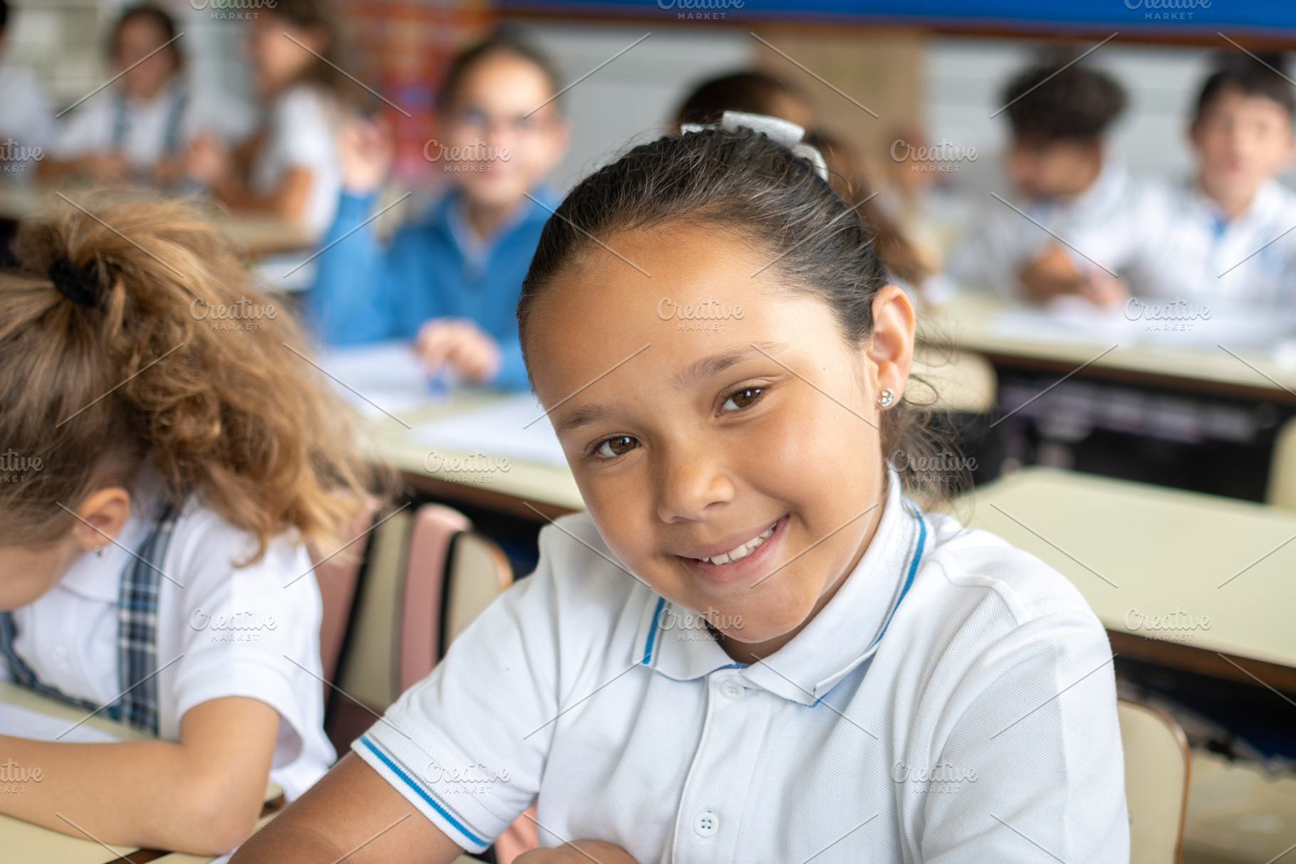 Smiling elementary school girl sitting in classroom, a Person Photo by etorres69