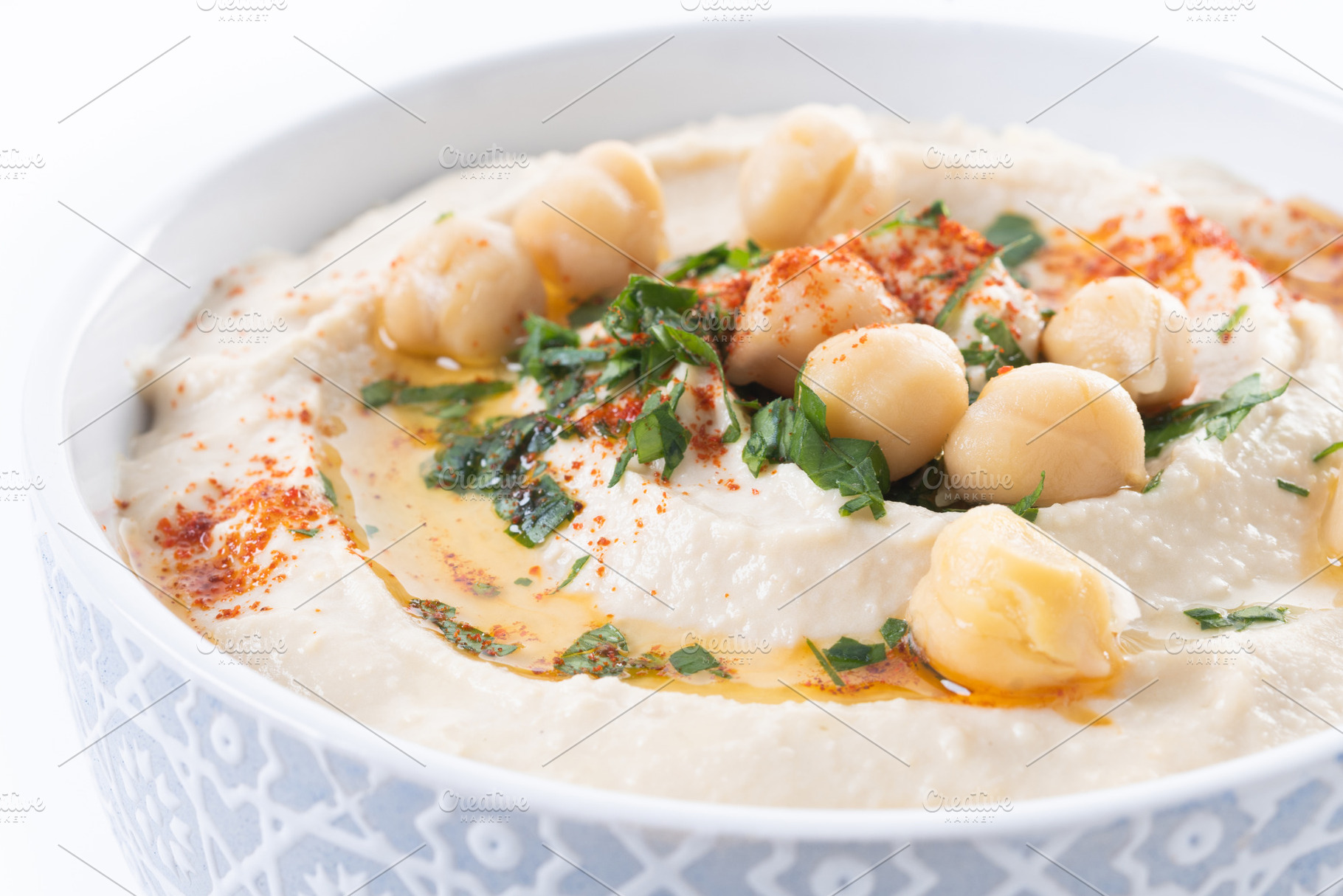 Chickpea hummus with olive oil, parsley and paprika in bowl on wooden table, a Food & Drink Photo by etorres69