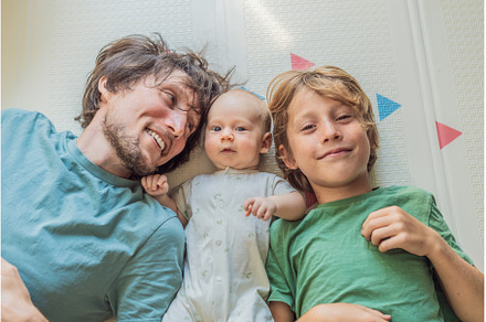 Father, son, and newborn baby lying