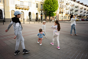 Children playing together in a lively city square with bright surroundings, a Person Photo by AS photostudio