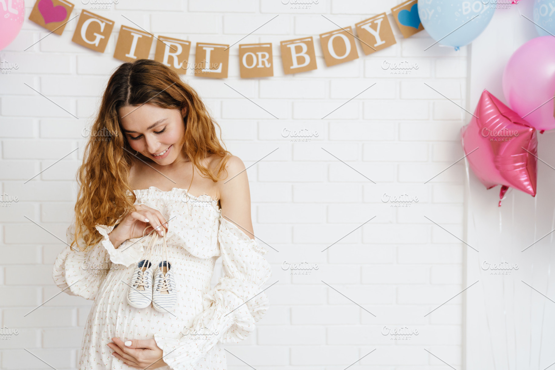 Young happy pregnant woman posing with baby shoes during gender party, a Person Photo by Dean Drobot