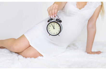 The pregnant woman holds an alarm, a Person Photo by yanadjana
