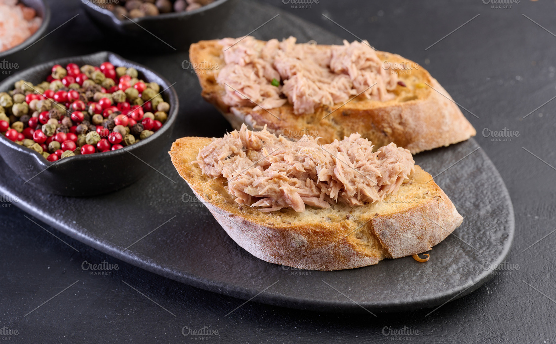 Tuna bruschetta on black slate with spices nearby., a Food & Drink Photo by ndanko