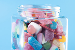 Hand reaching for colorful gummy candies in glass jar, a Food & Drink Photo by etorres69