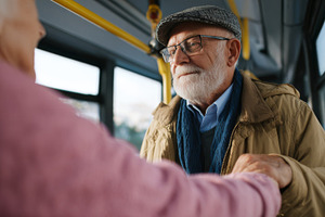 Elderly Caucasian man with a beard and glasses warmly assisting an older woman, a Business Photo by ImageMir