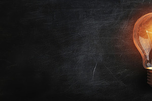 Glowing Light Bulb on Dark Chalkboard Background, an Abstract Photo by Natalia Klenova's Shop