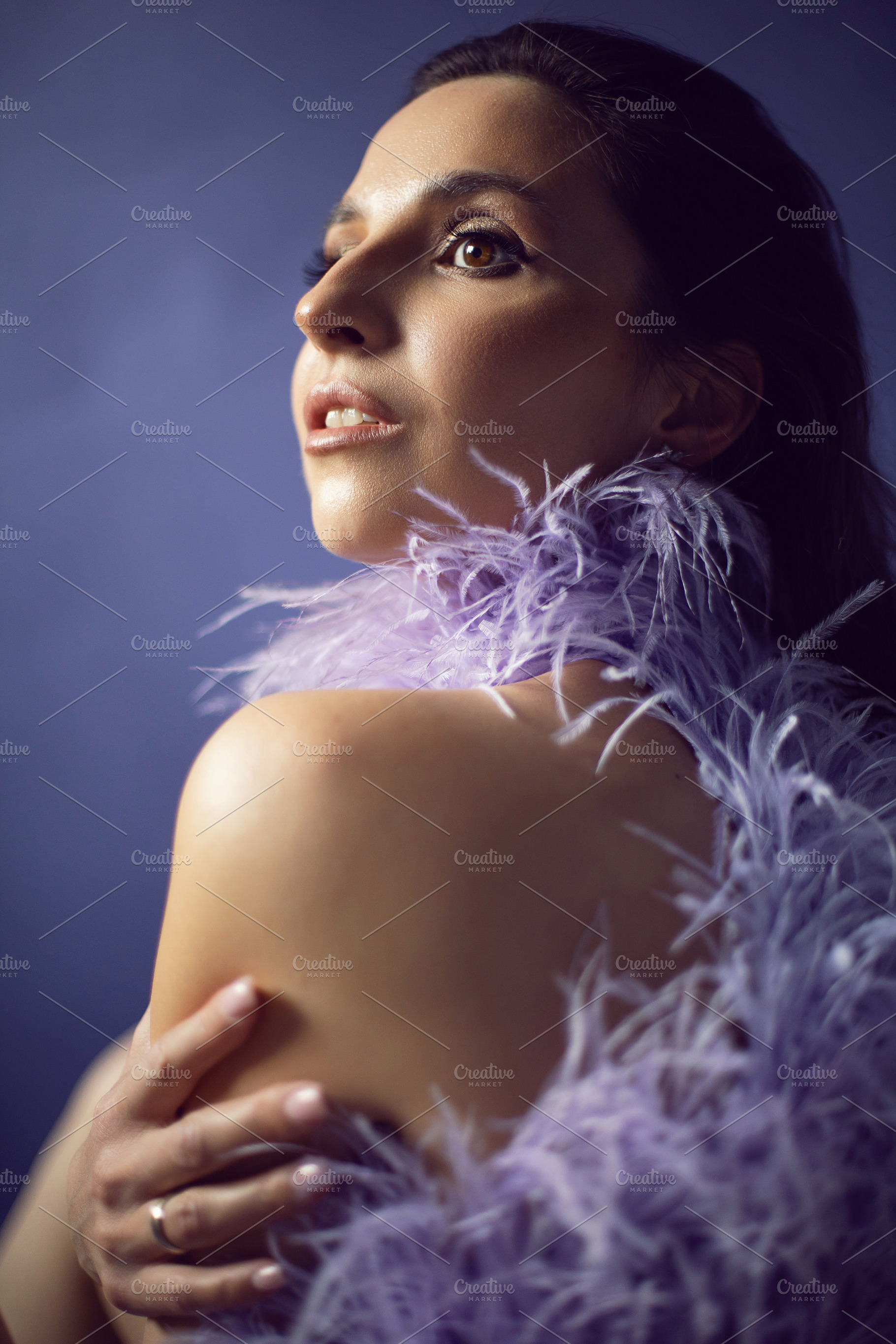 portrait woman in an evening purple dress with feathers stands in the backgroun, a Person Photo by SaulichPhoto