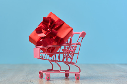 A gift wrapped in red paper in a miniature shopping cart on a bl, a Holiday Photo by ndanko