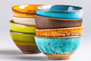 Stacked colorful ceramic bowls on white background, a Food & Drink Photo by AlyaAnd