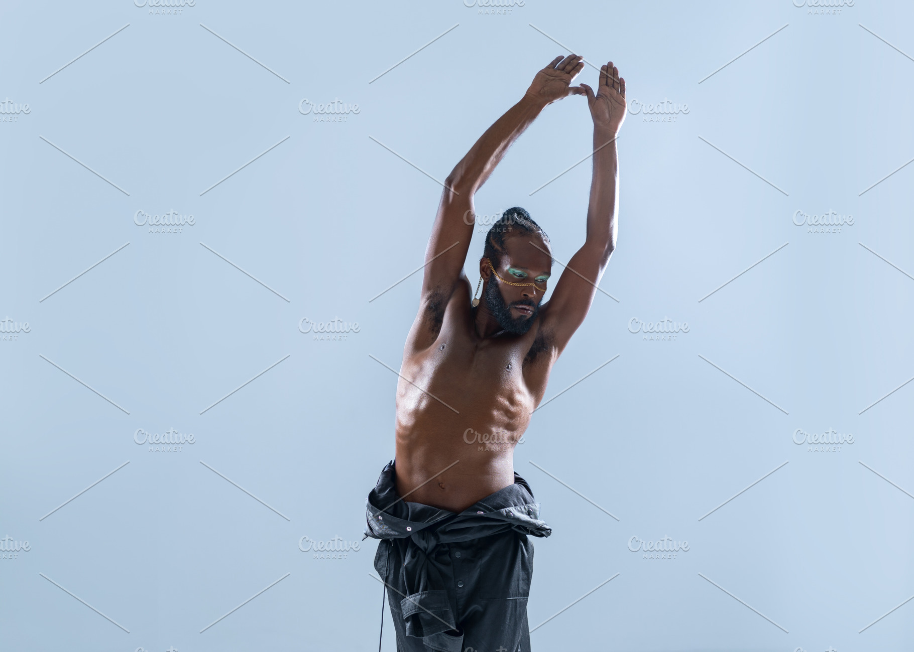 Black shirtless gay model with hands raised posing in blue studio, a Person Photo by andreonegin market