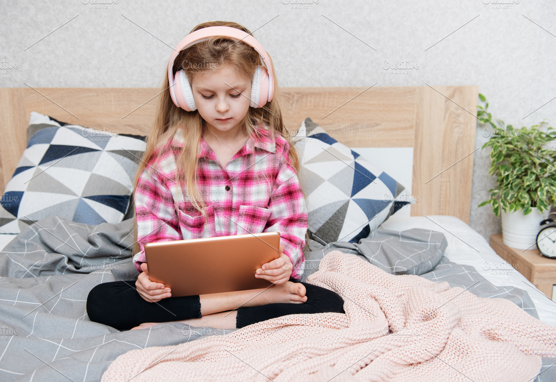 Cute Little girl sitting on bed and using tablet at home, a Person Photo by Olena Rudo
