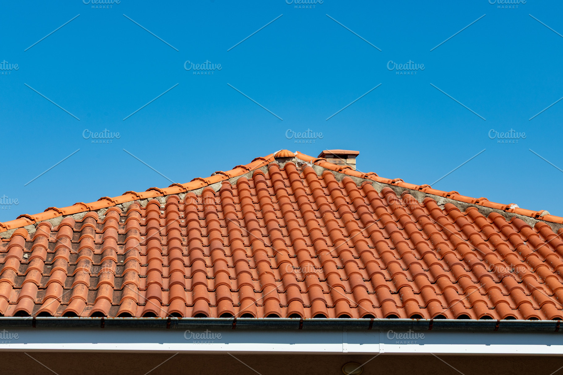 Close-up of a terracotta tiled roof under a clear blue sky, highlighting archit, an Architecture Photo by Ales Munt