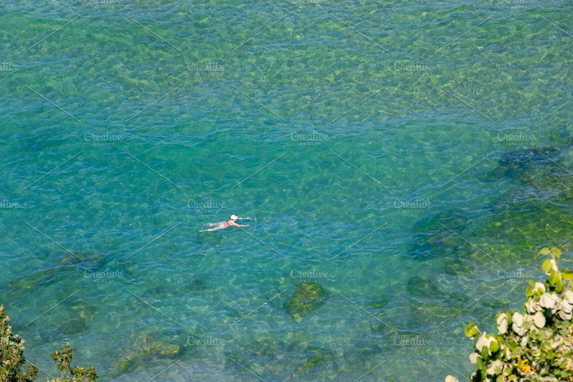A lone swimmer in crystal-clear turquoise water, viewed from above. Sunlit sea, a Holiday Photo by Ales Munt