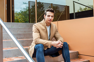Confident young man sitting on modern outdoor steps, a Person Photo by RF Images