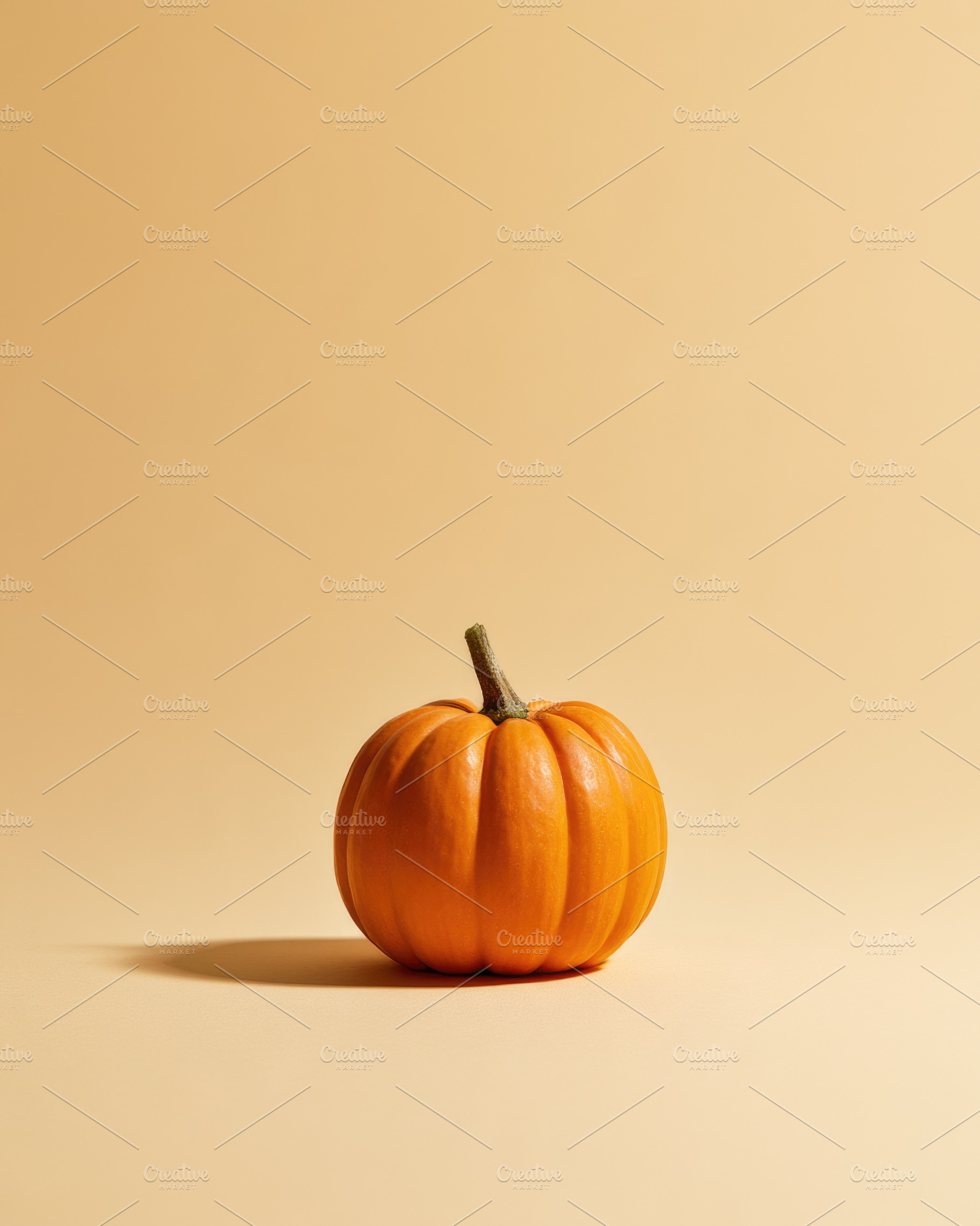 Single orange pumpkin on warm beige Halloween background, a Nature Photo by José Manuel Gelpi