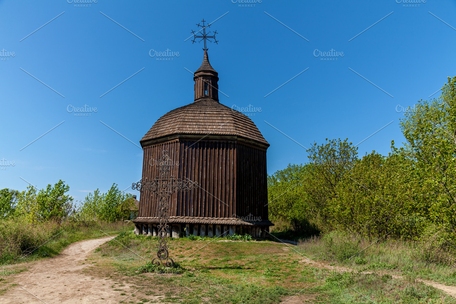 Old wooden chapel with cross in rural spring landscape, an Architecture Photo by Photostock