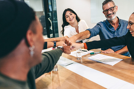 Diverse group of businesspeople bringing their fists together in a boardroom, a Person Photo by Jacob Lund