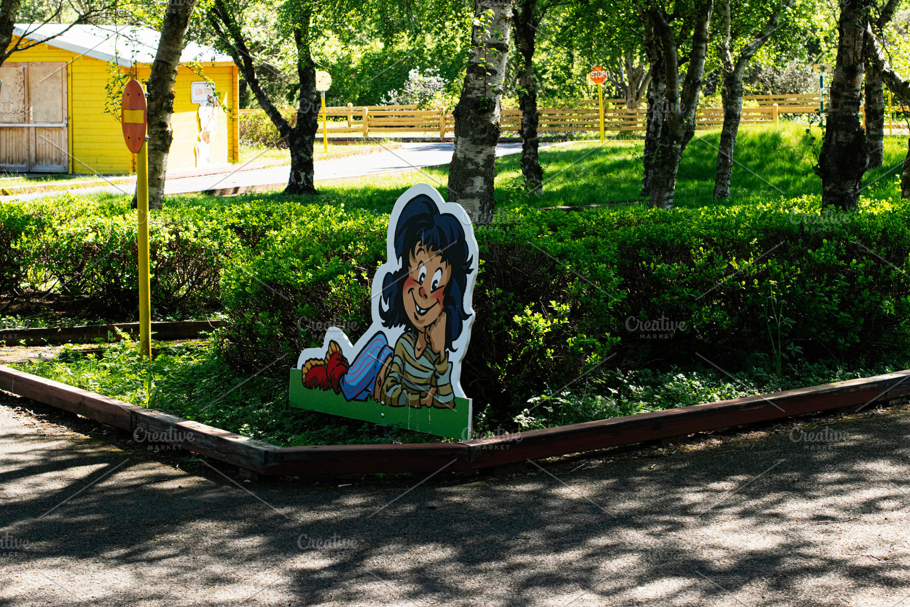 Colorful cartoon display in a sunny park with a vibrant yellow building, a Photo by AS photostudio
