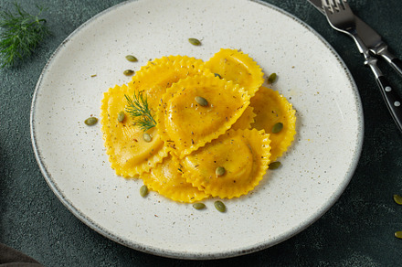Homemade Pumpkin Ravioli with butter on a dark concrete background. Top view, a Food & Drink Photo by Budarinphoto