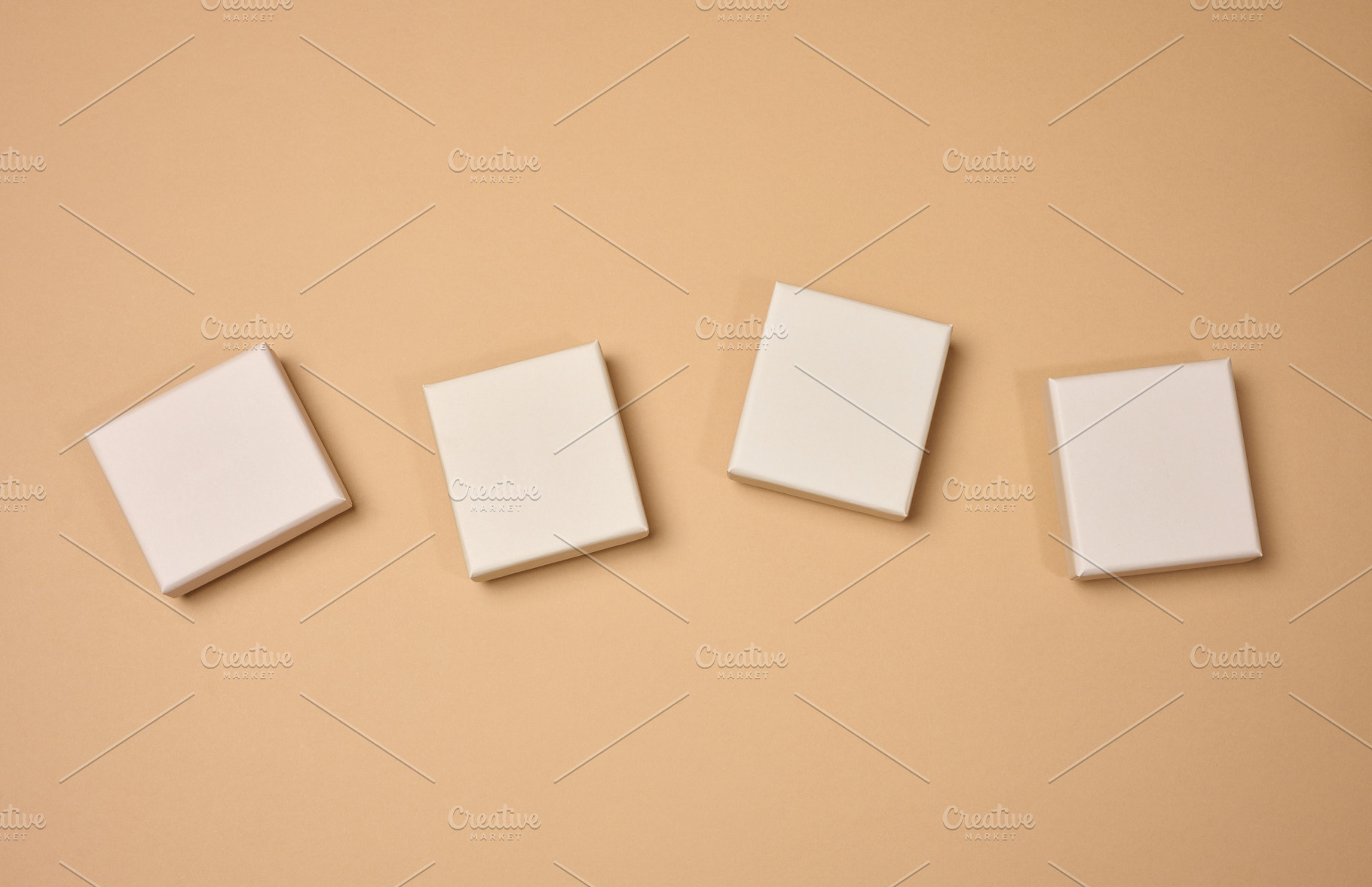 Four beige square cardboard boxes on a beige background., a Background Photo by ndanko