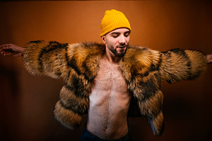 Confident man wearing fur coat with open arms, a Photo by karrastock