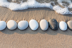 Assorted pebbles aligned on a beach with a calm ocean backdrop, an Abstract Photo by Natalia Klenova's Shop