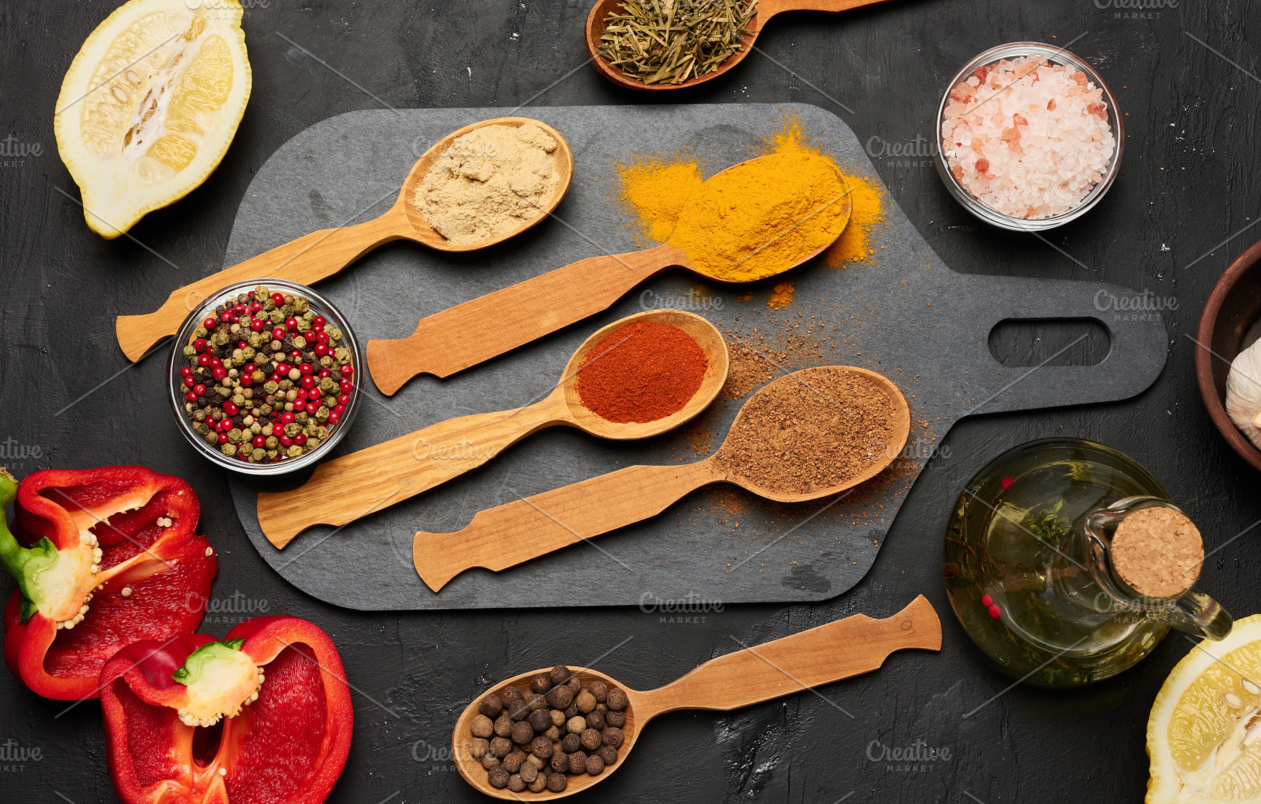 Wooden spoons with ground spices on a black board surrounded by, a Food & Drink Photo by ndanko