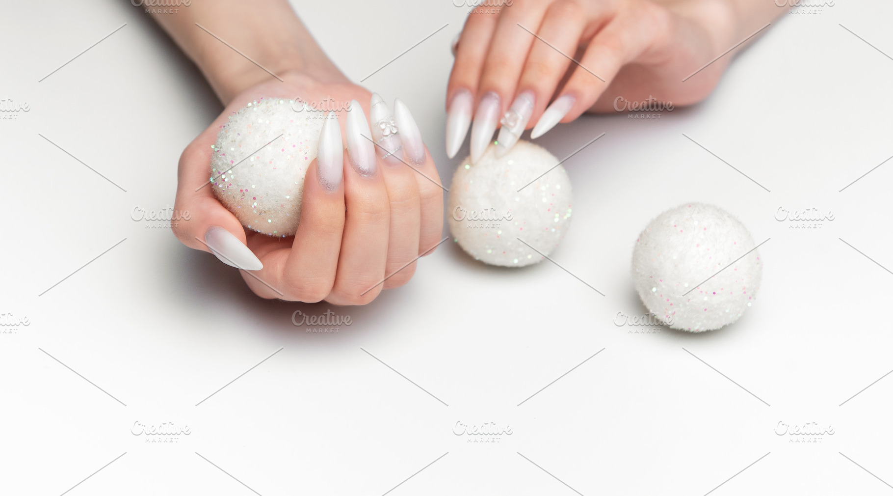 Woman hands holding sparkling christmas ornaments with long nail, a Photo by Olena Rudo