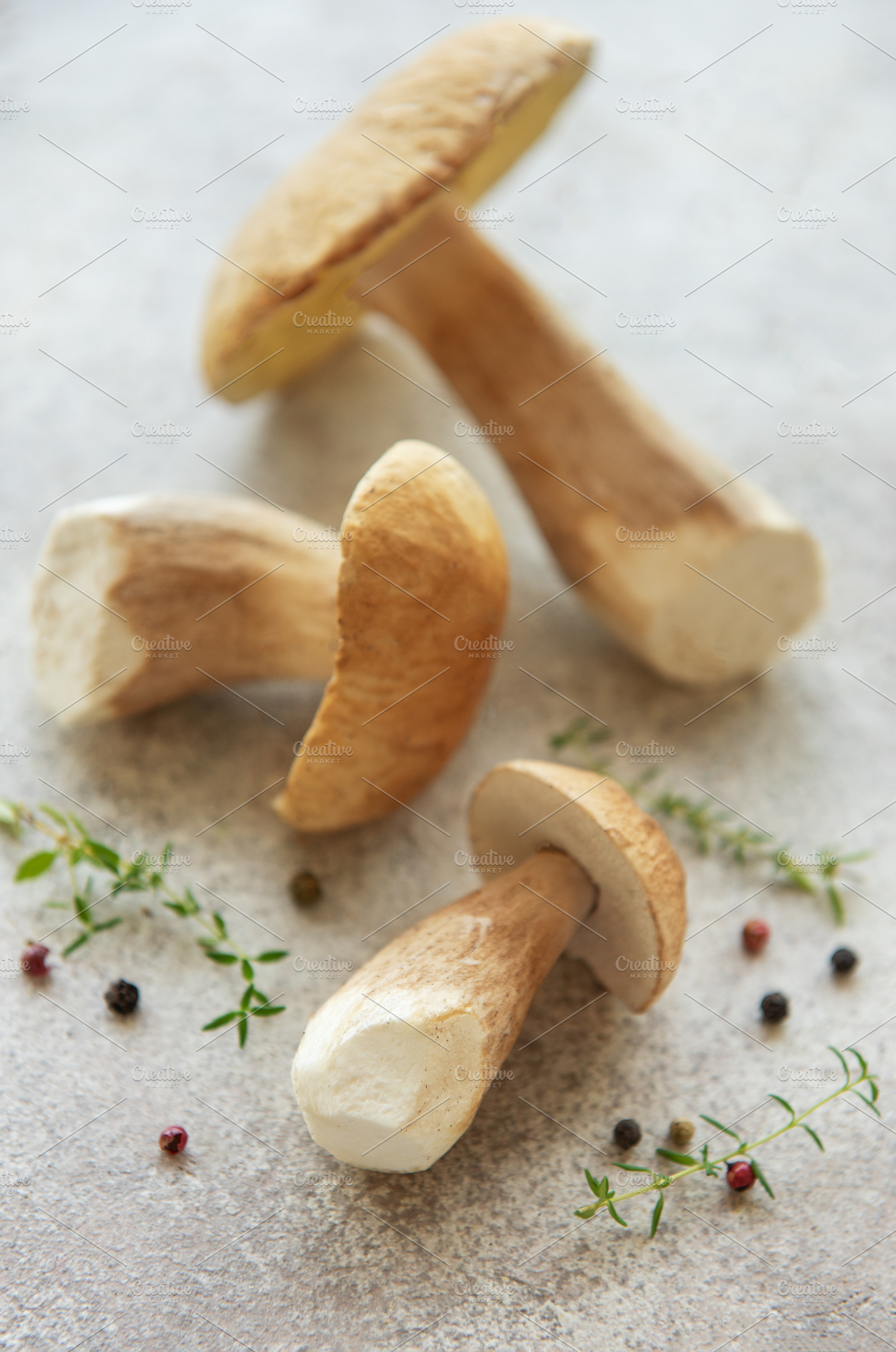 Fresh porcini mushrooms with thyme and peppercorns on gray backg, a Food & Drink Photo by Olena Rudo