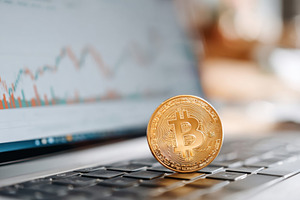 Bitcoin on laptop keyboard with stock market graph, a Business Photo by AlyaAnd