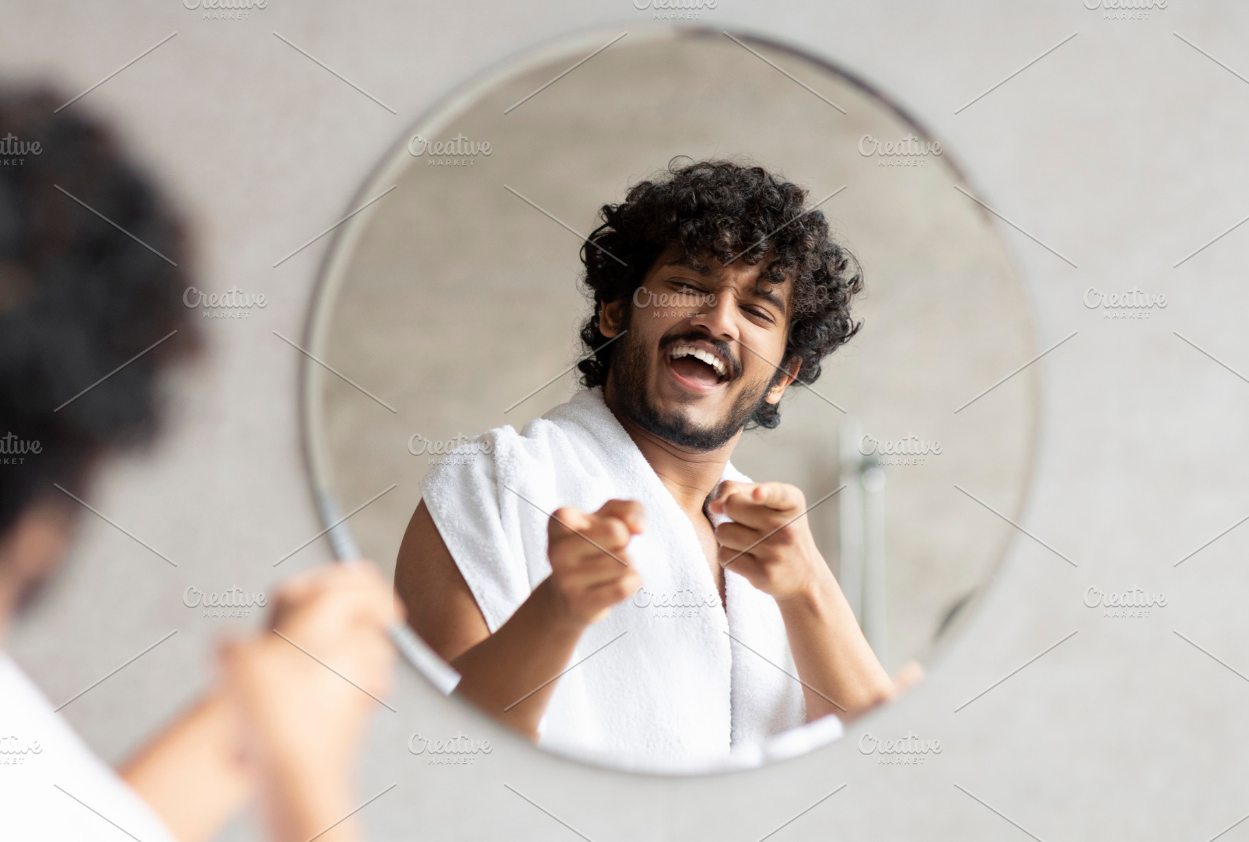 Excited indian guy pointing at mirror in bathroom with two fingers, standing wi, a Person Photo by Prostock-Studio