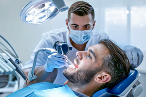 Male dentist performing treatment on patient, a Health & Medical Photo by DanFLCreativo