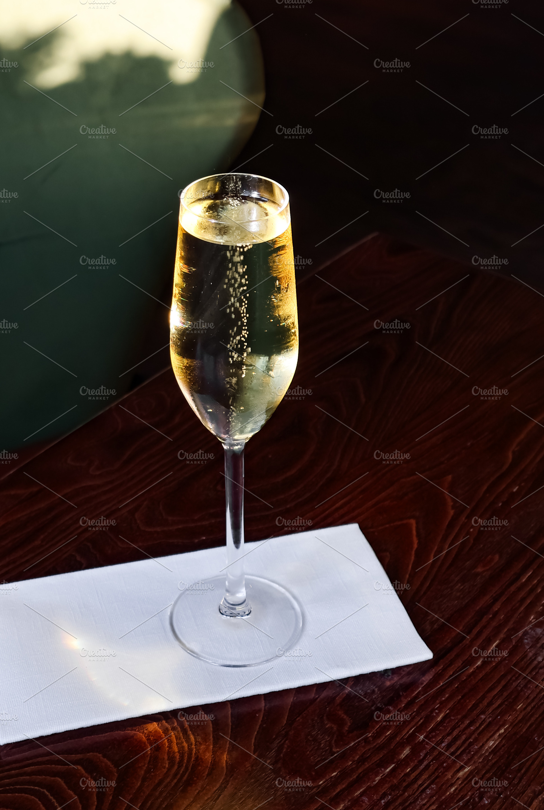 Glass of sparkling wine with rising bubbles on a wooden table, c, a Photo by Studio ANNA