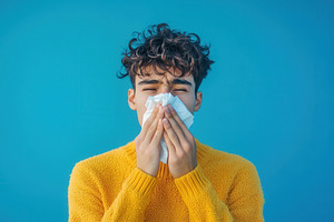 Man in yellow sweater blowing nose, a Photo by Pavel_design